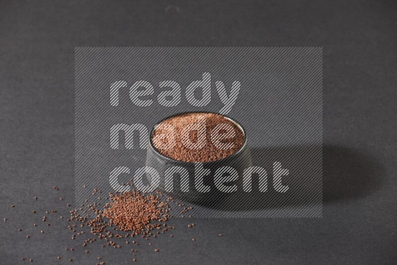 وعاء فخاري أسود ممتلئ ببذور حب الرشاد على أرضية سوداء