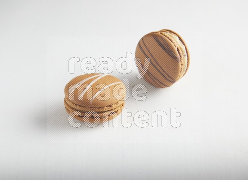 45º Shot of of two assorted Brown Irish Cream, and light brown  Almond Cream macarons on white background