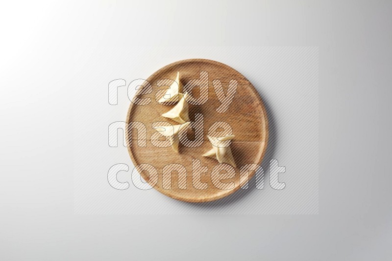 Five Sambosas on a wooden round plate on a white background