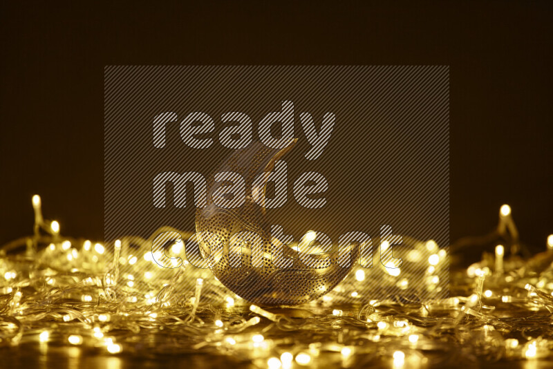 A traditional ramadan lantern surrounded by glowing fairy lights in a dark setup