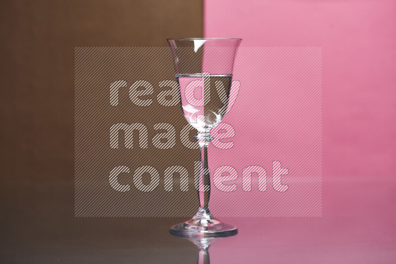 The image features a clear glassware filled with water, set against brown and pink background