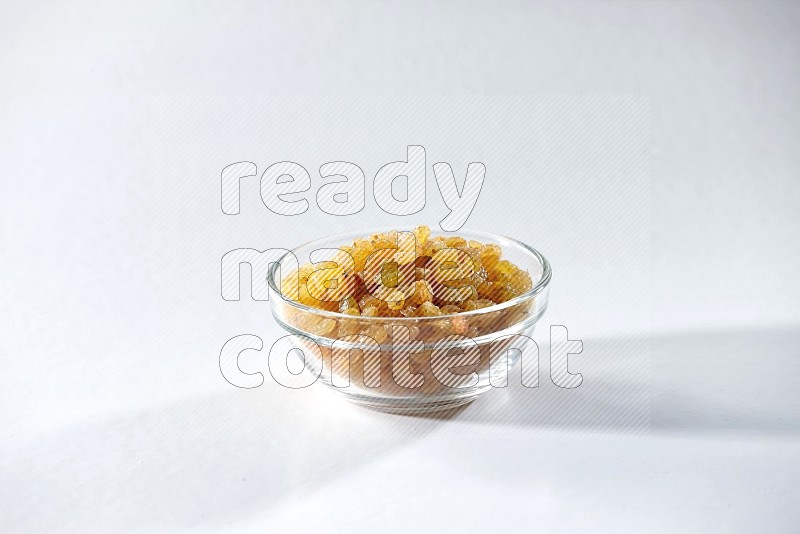 A glass bowl full of raisins on a white background in different angles