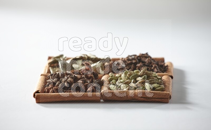 4 squares of cinnamon sticks full of cardamom, star anise, cloves and bay laurel leaves on white flooring