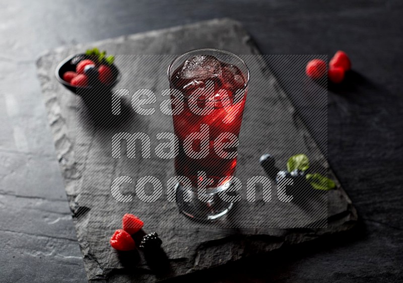 A glass of mixed berries juice on black background