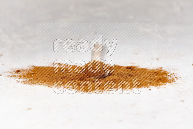 A wooden spoon full of ground paprika powder and surrounded with the powder on white background