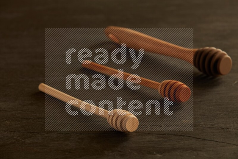 Wooden honey dipper on black slate background