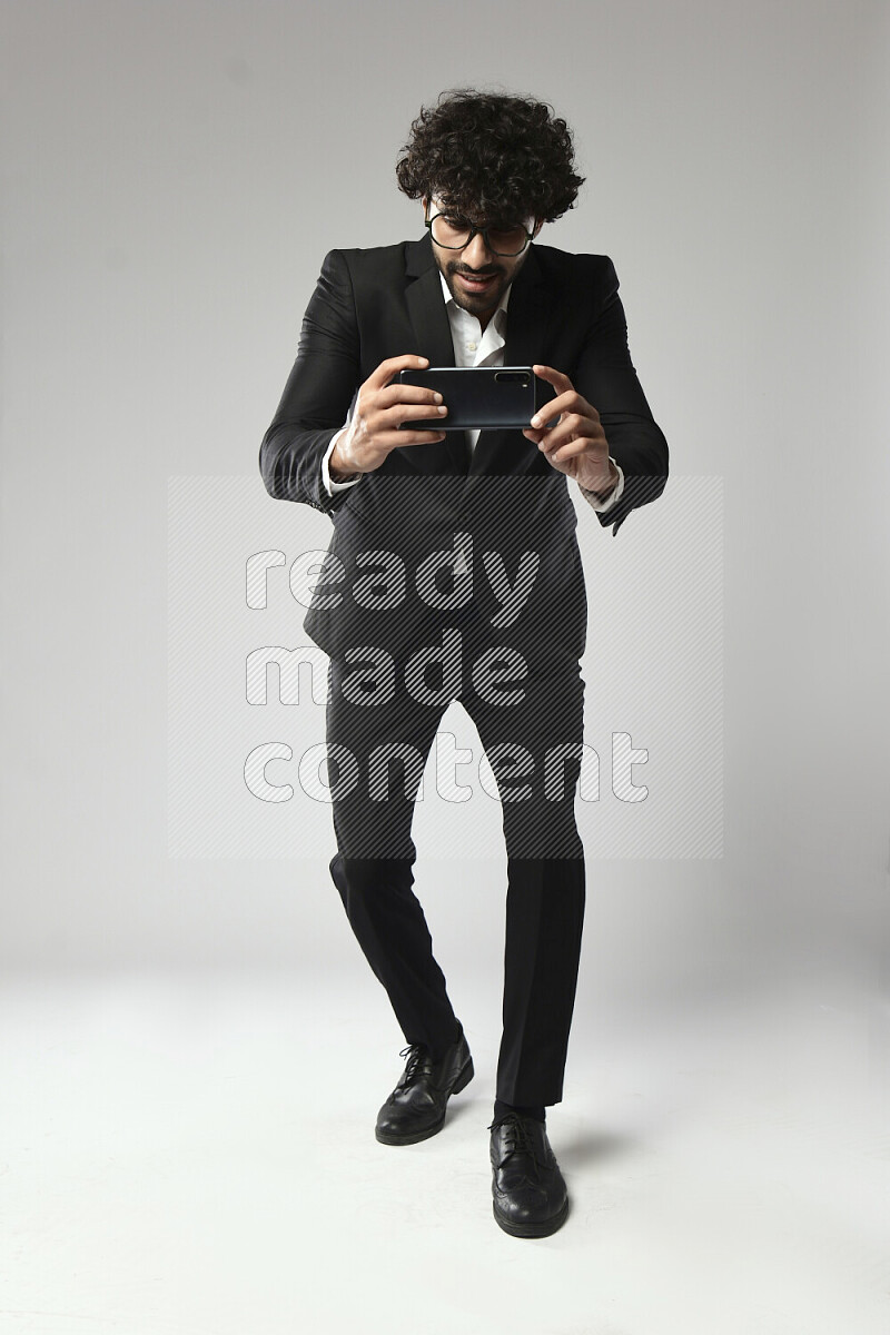 A man wearing formal standing and shooting with his phone on white background