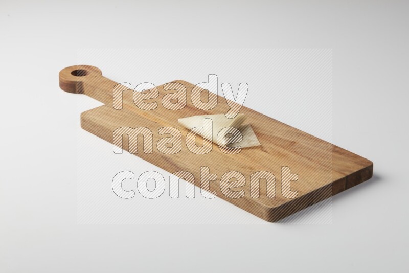One uncooked samosa on a wooden cutter on a white background