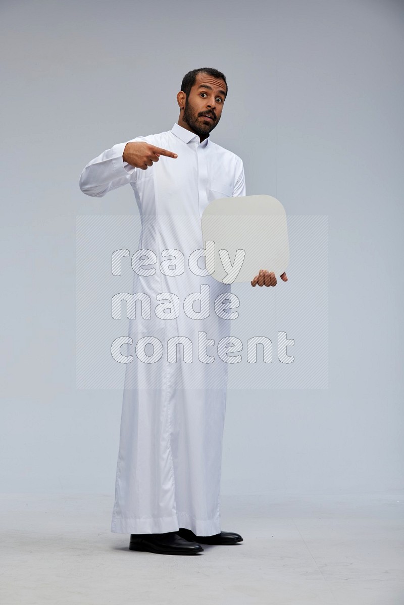 Saudi man wearing Thob standing holding social media sign on Gray background