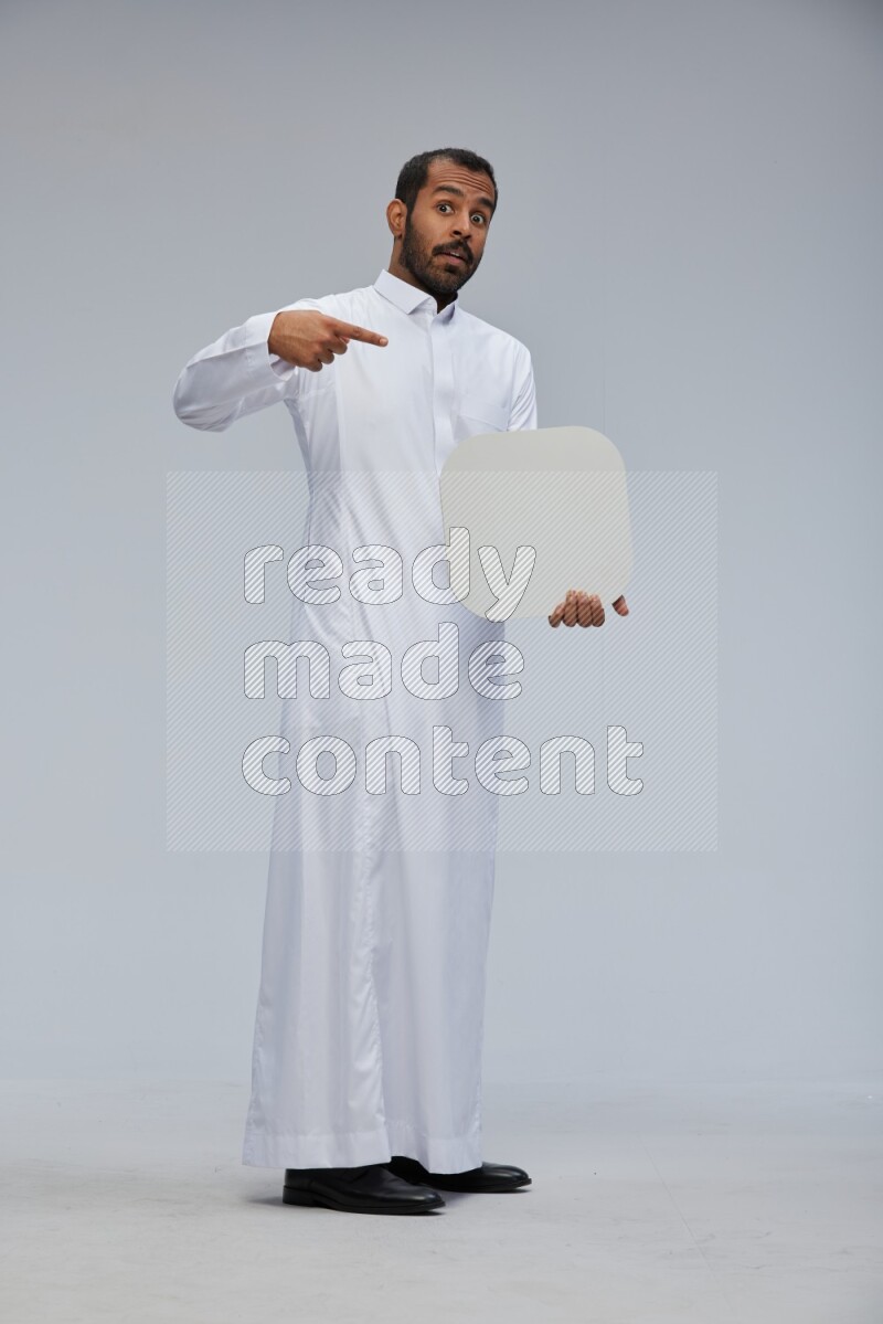Saudi man wearing Thob standing holding social media sign on Gray background