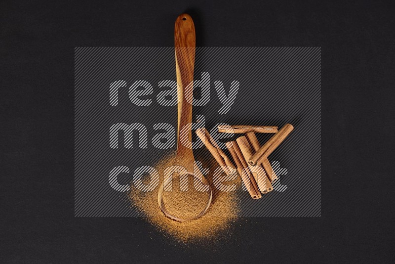 Cinnamon powder in a spoon ladle and spreaded on the floor beside it cinnamon sticks on the floor on black background in different angles