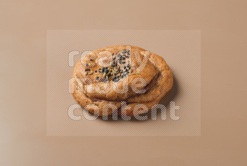 a whole Hasawi cookie with grains on a brown background