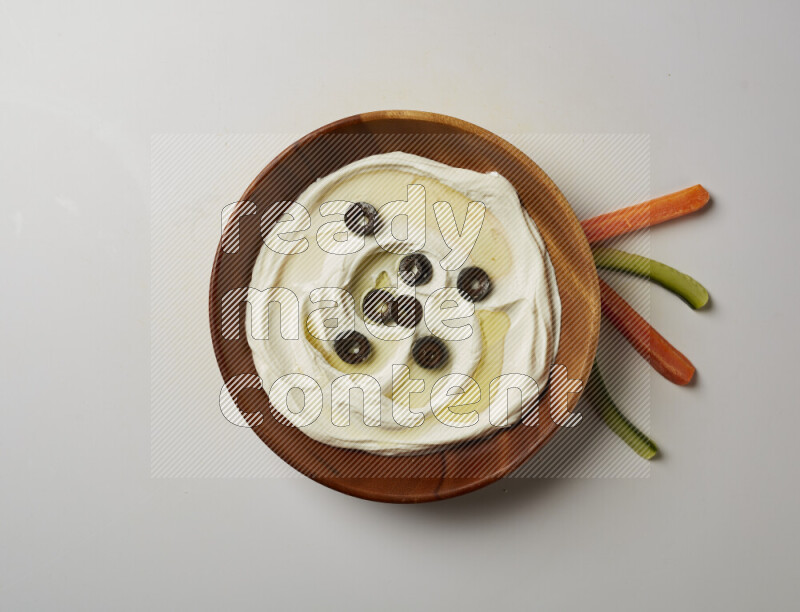 Lebnah garnished with sliced olives in a wooden plate on a white background