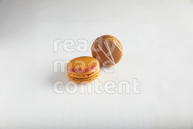 45º Shot of of two assorted Brown Irish Cream, and Orange Exotic macarons on white background