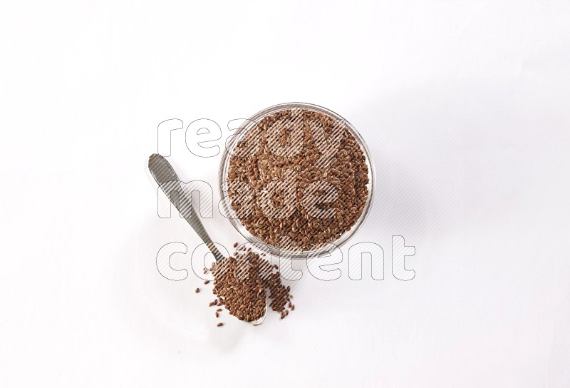 A glass bowl full of flax and a metal spoon full of the seed on a white flooring in different angles