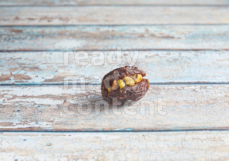 pistachio stuffed madjoul date on a light blue wooden background