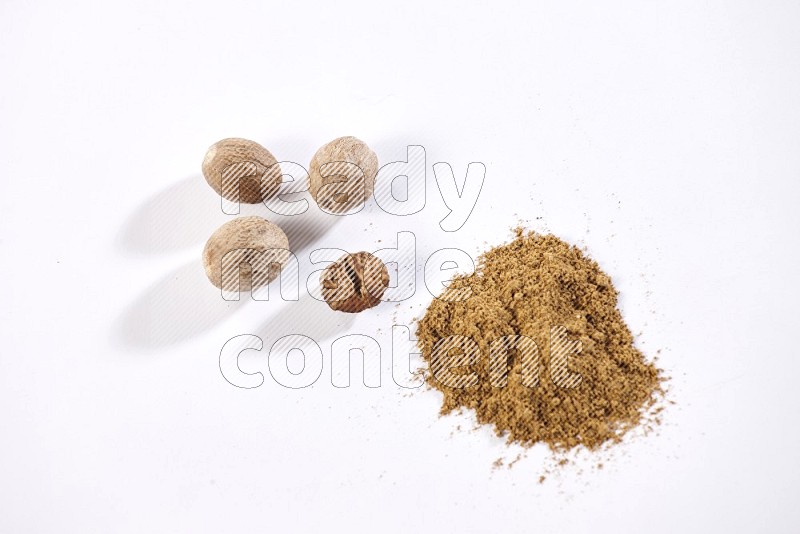 Nutmeg whole seeds with nutmeg powder beside it on a white flooring