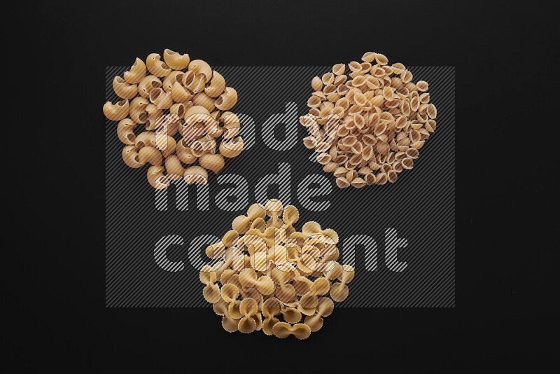 Different pasta types in bunches on black background