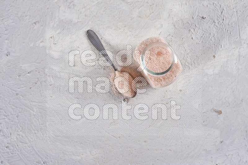 A glass jar full of fine himalayan salt on white background