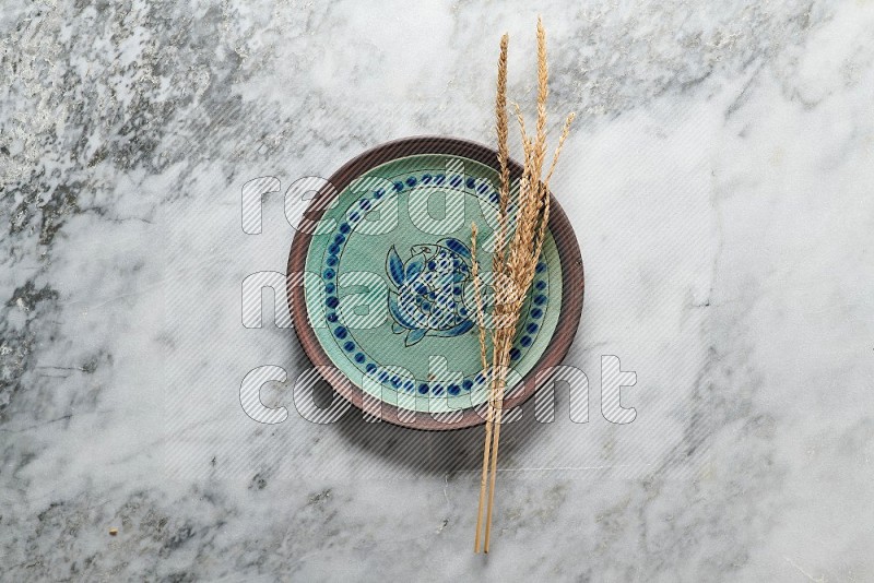 Wheat stalks on Decorative Pottery Plate on grey marble flooring, Top view