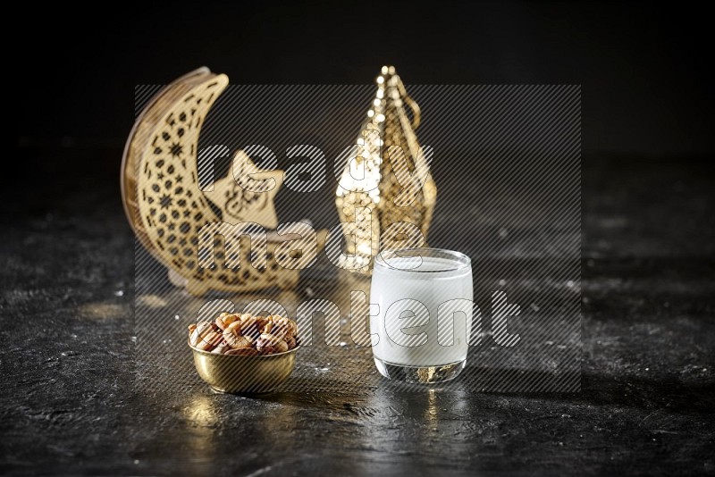 Nuts in a metal bowl with sobia beside golden lanterns in a dark setup