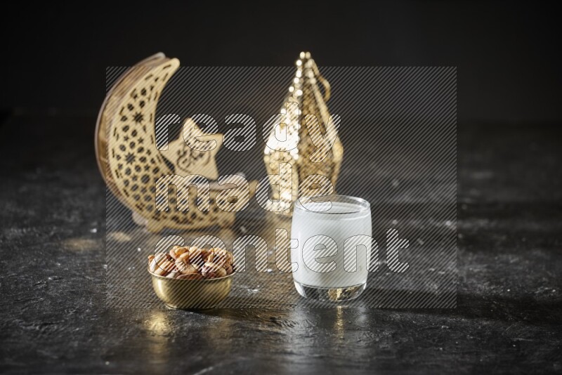 Nuts in a metal bowl with sobia beside golden lanterns in a dark setup