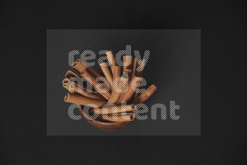 Cinnamon Sticks in a wooden bowl on black background