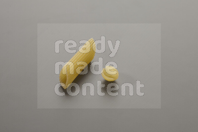 Penne pasta with other types of pasta on grey background