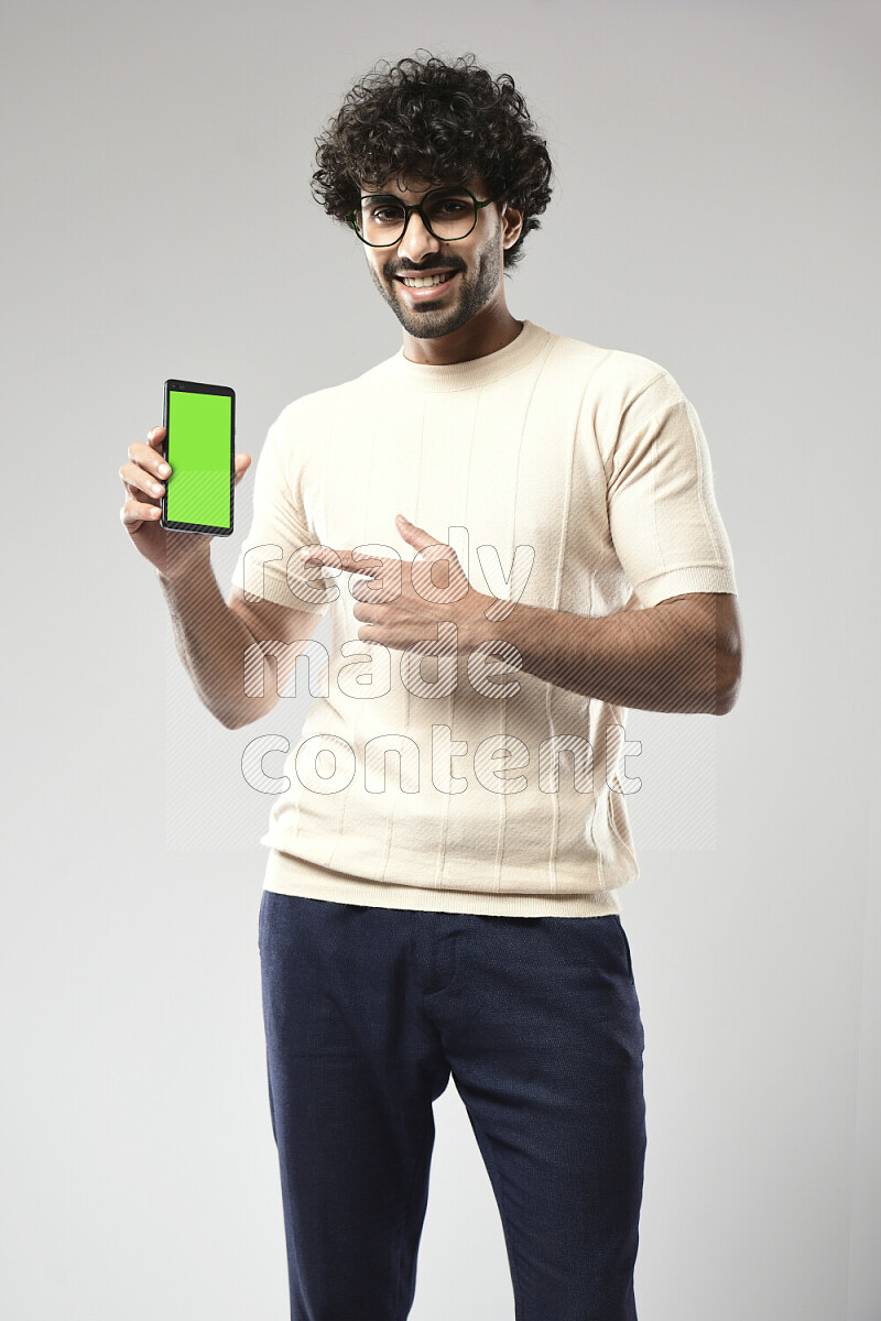 رجل يرتدي ملابس كاجوال يحمل هاتف علي خلفية بيضاء
