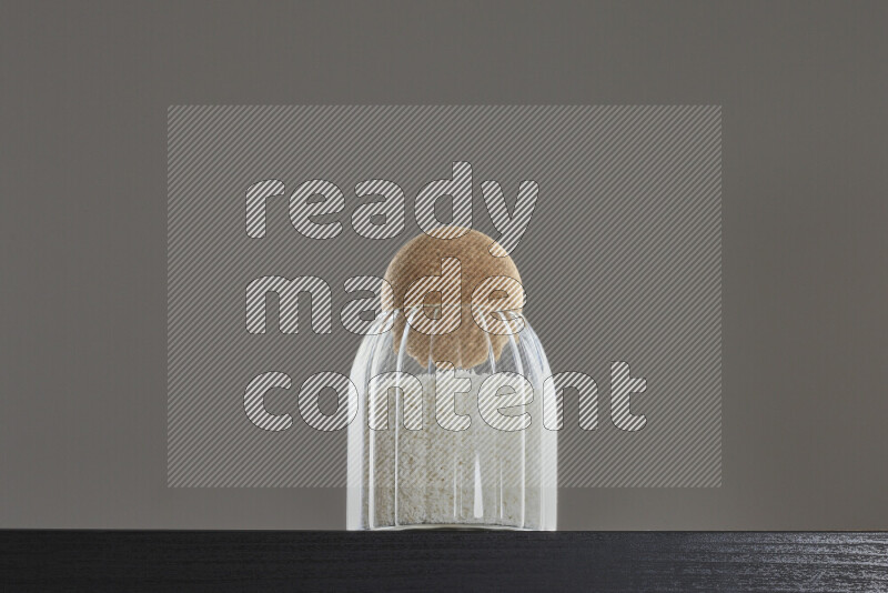 Desiccated coconut in a glass jar on black background