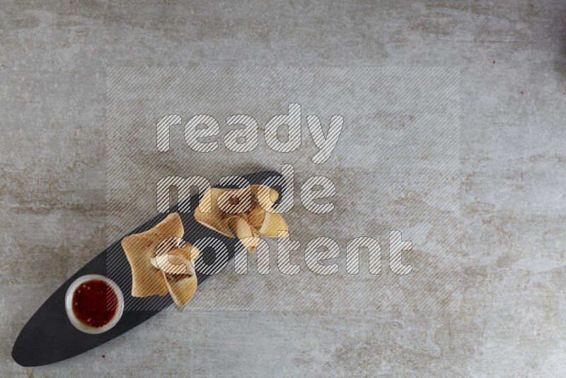 wonton cups with soy sauce ramkin on oval slate on grey textured counter top