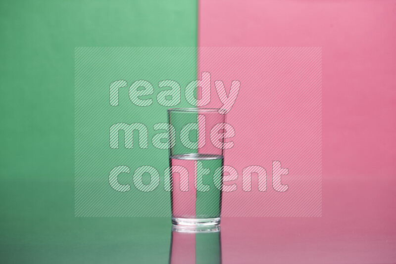 The image features a clear glassware filled with water, set against green and pink background