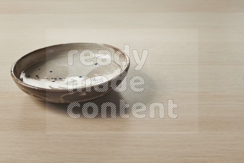 صحن فخاري متعدد الألوان على خلفية خشبية فاتحة