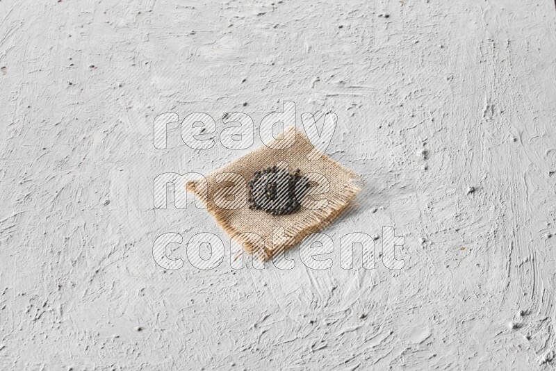 Black pepper on burlap fabric on a textured white flooring