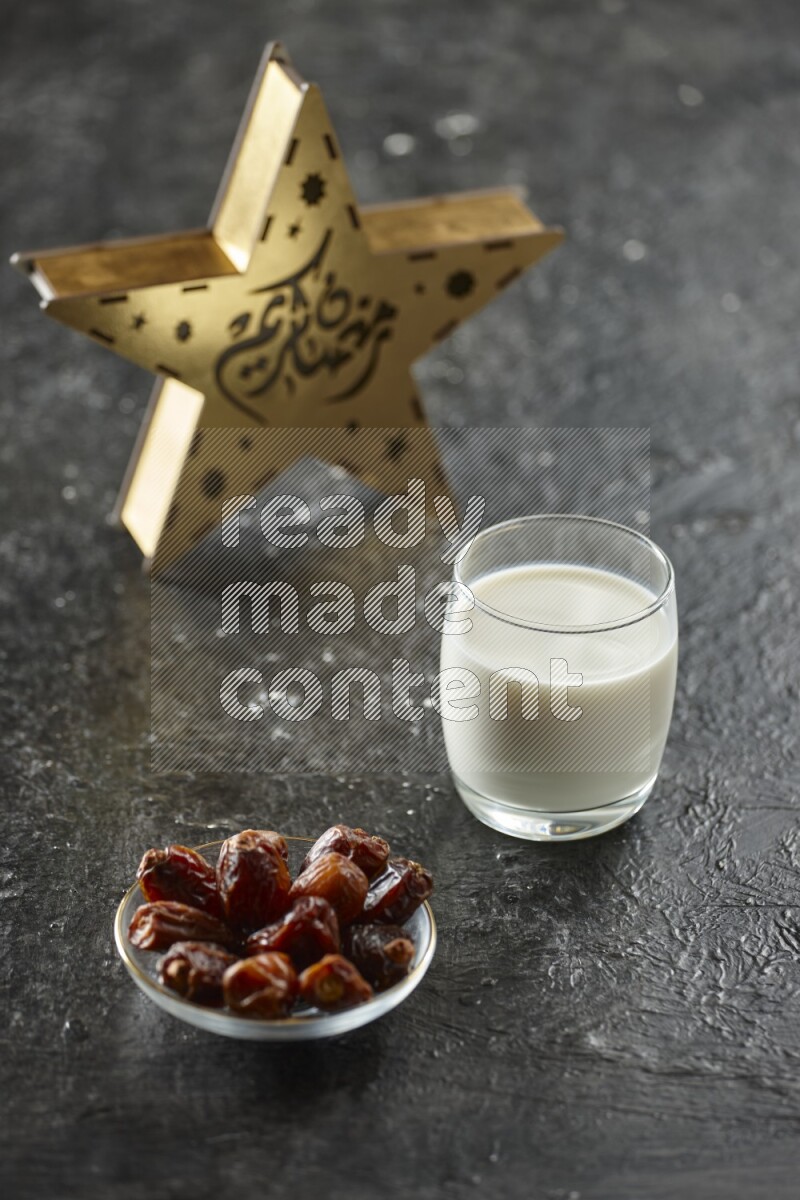 A wooden golden star lantern with different drinks, dates, nuts, prayer beads and quran on textured black background