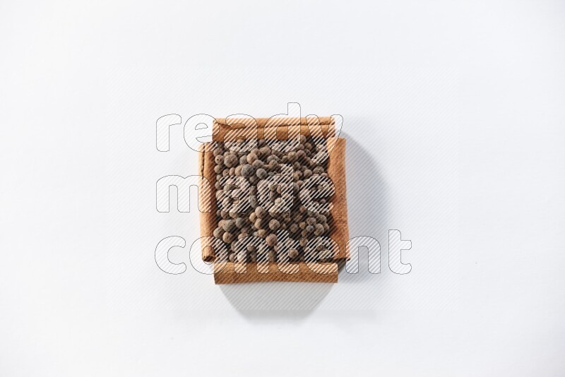 A single square of cinnamon sticks full of allspice on white flooring