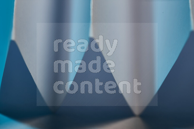 A close-up abstract image showing sharp geometric paper folds in blue gradients