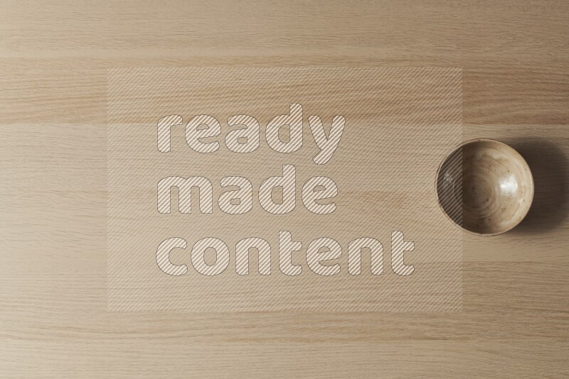 A beige pottery bowl on light wooden background
