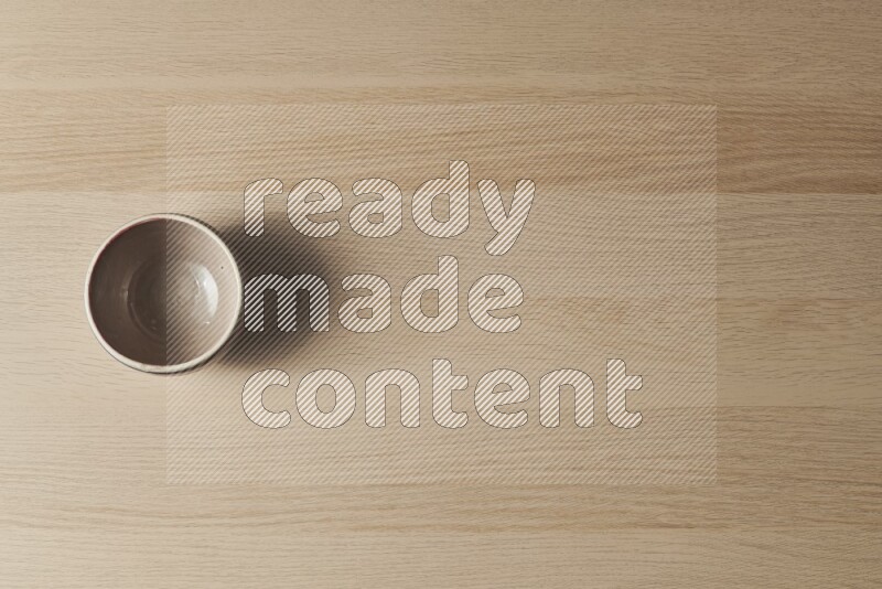 وعاء فخاري متعدد الألوان على خلفية خشبية فاتحة