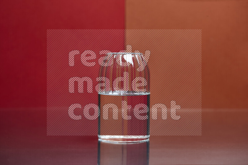 The image features a clear glassware filled with water, set against red and dark orange background