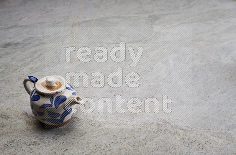 A Pottery Teapot On Grey Marble Flooring