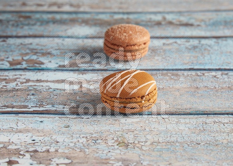 45º Shot of of two assorted Brown Irish Cream, and Brown Hazelnuts macarons  on light blue background