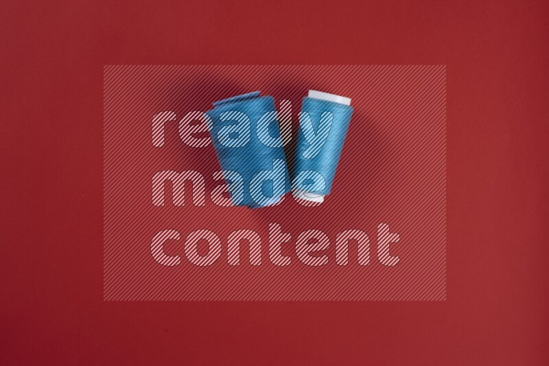 مجموعة من أدوات الخياطة والتفصيل زرقاء وحمراء اللون على خلفية حمراء