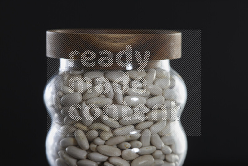 White beans in a glass jar on black background
