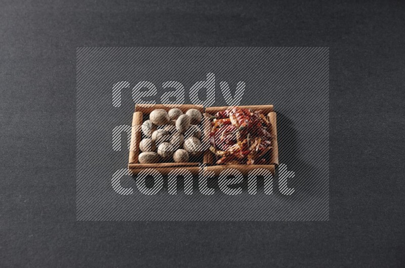 2 squares of cinnamon sticks full of nutmegs and dried red chilis on black flooring