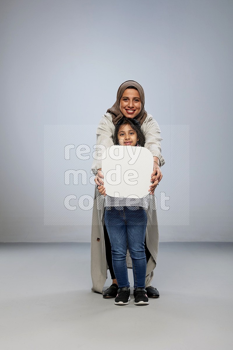 Mom and daughter standing holding social media sign on gray background