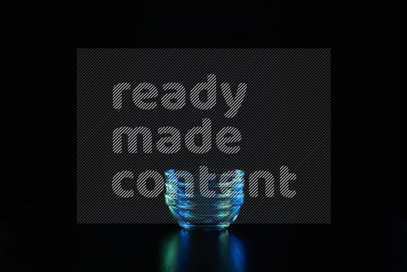 Glassware with rim light in blue and green against black background