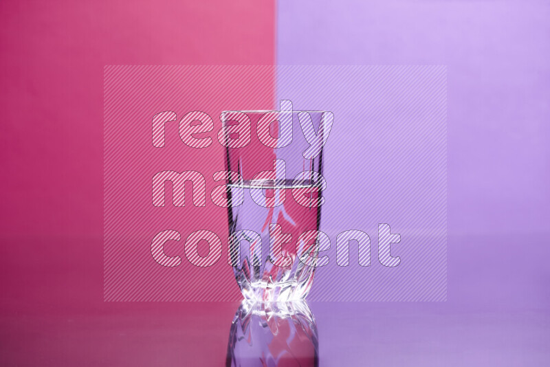 The image features a clear glassware filled with water, set against pink and light purple background