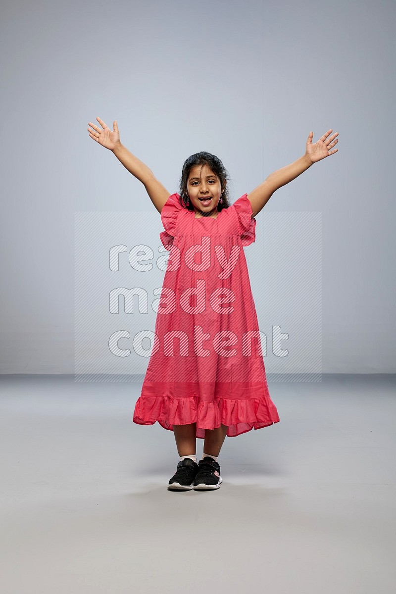 A girl standing interacting with the camera on gray background