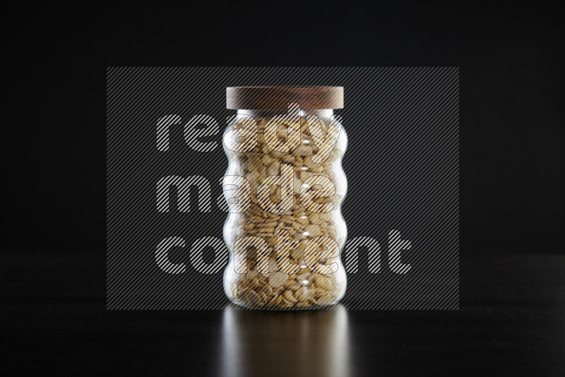 Crushed beans in a glass jar on black background